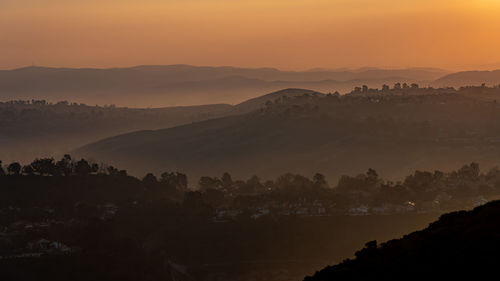 Scenic view of silhouette mountains against orange sky