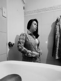 Young woman looking away while standing in bathroom