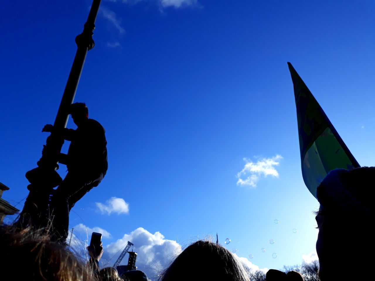 LOW ANGLE VIEW OF SILHOUETTE PEOPLE AGAINST BLUE SKY