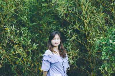 Portrait of young woman standing against plants