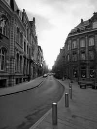 Empty road amidst buildings in city against sky