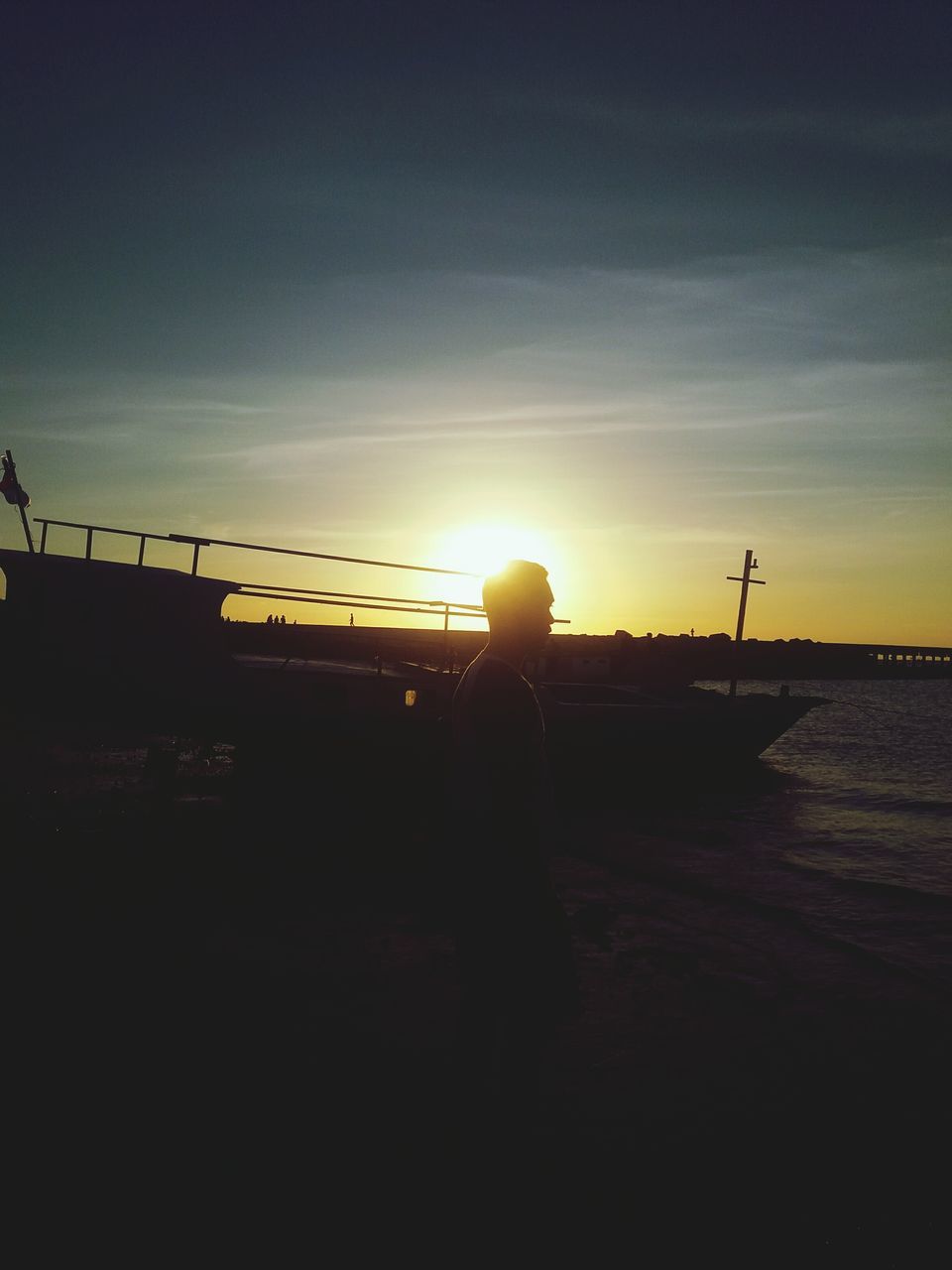 SILHOUETTE MAN STANDING IN SEA AGAINST SUNSET SKY