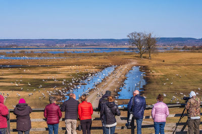 Rear view of people standing on land against clear sky