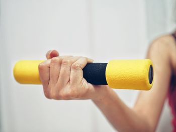 Cropped hand of woman lifting dumbbells in gym