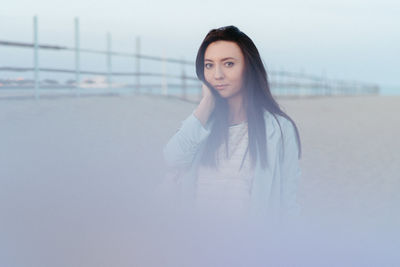 Portrait of young woman standing against sky