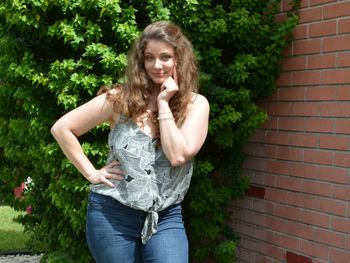 Portrait of teenage girl standing against brick wall