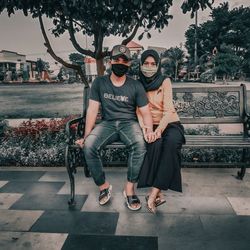 Full length portrait of young couple sitting outdoors