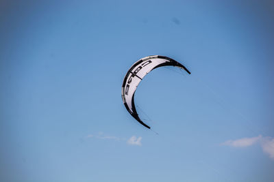 Low angle view of person paragliding against blue sky