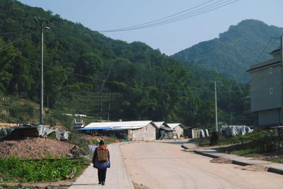 Man on road amidst trees against sky