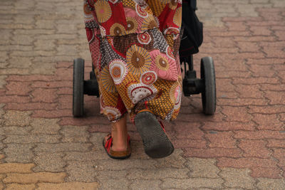 Low section of woman with baby carriage walking on pathway