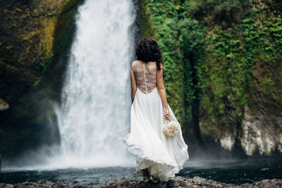 Woman standing by waterfall