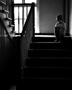 Boy using smart phone while sitting on steps at home