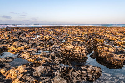 Scenic view of rocks on beach against sky