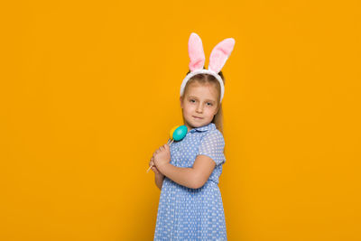 Portrait of cute girl holding toy against yellow background