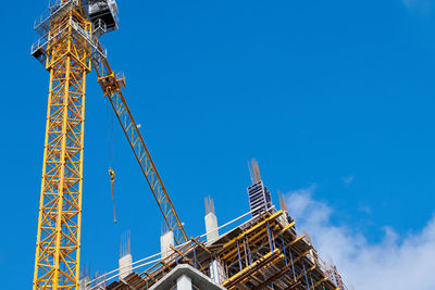 Low angle view of crane against blue sky