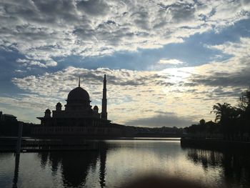 Panoramic view of lake by building against sky during sunset