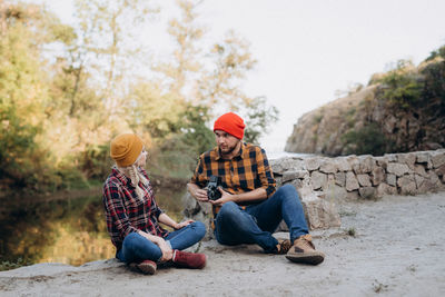 People sitting on rock against trees