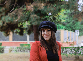 Portrait of smiling woman standing against trees