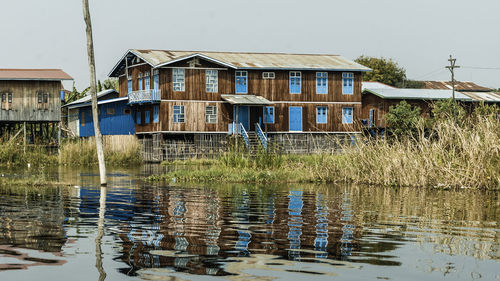 Wooden house by lake against clear sky