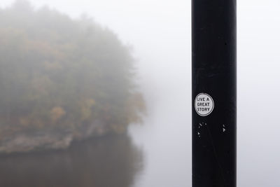 Close-up of text on glass against sky