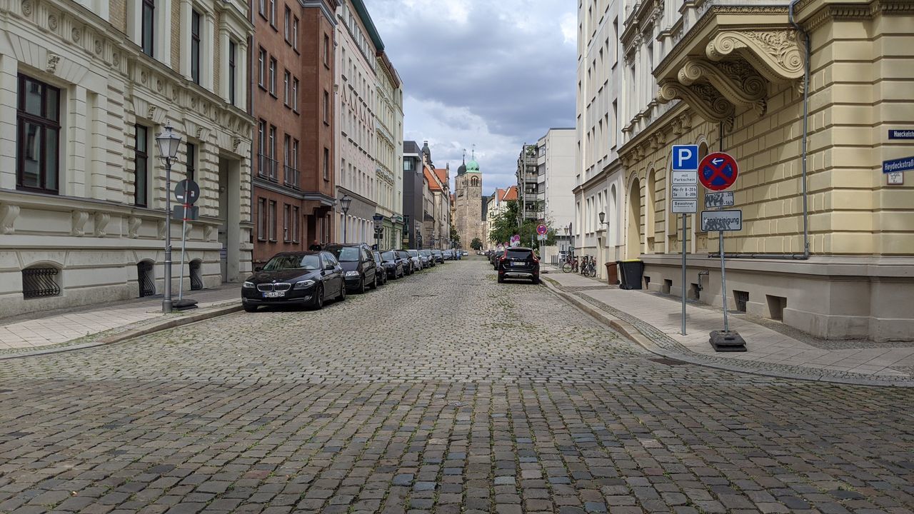 CARS ON FOOTPATH BY BUILDINGS IN CITY