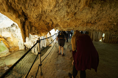 Rear view of people walking in cave