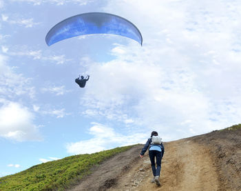 Woman paragliding over friend against sky