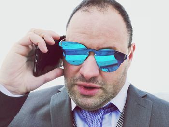 Businessman in sunglasses talking on mobile phone outdoors