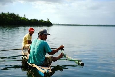 Men sitting in water against sky