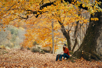 Man sitting on leaves during autumn