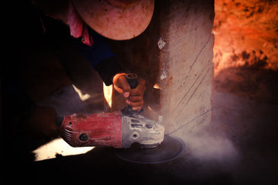 Cropped hand of manual worker cutting wall with electric saw in workshop