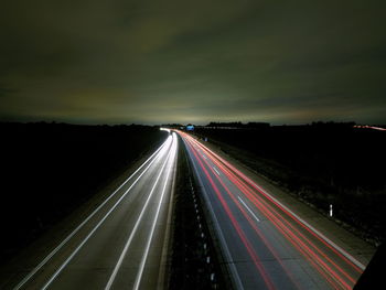 Light trails on road against sky at night