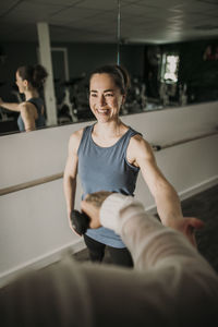 Smiling female personal trainer coaches a person lifting weights