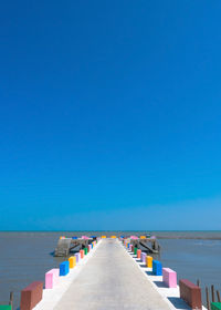 The cement bridge extends into the sea. with colorful barrier panels in the blue sky