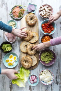 Breakfast, bagels, vegetables, salmon and ham, hands taking ingredients