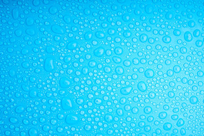 Full frame shot of water drops on blue background