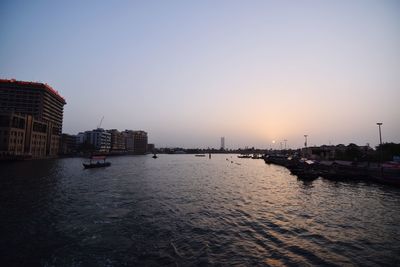 City buildings by sea against sky during sunset