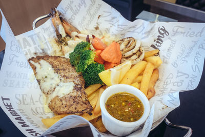 Directly above shot of grilled seafood with vegetables and french fries on paper