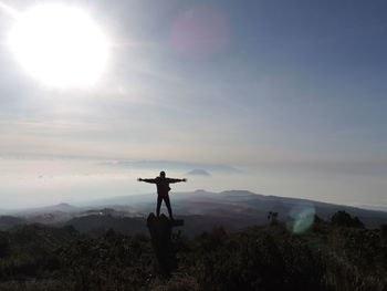 Silhouette man standing on tree stump