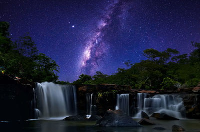 Scenic view of waterfall against sky at night