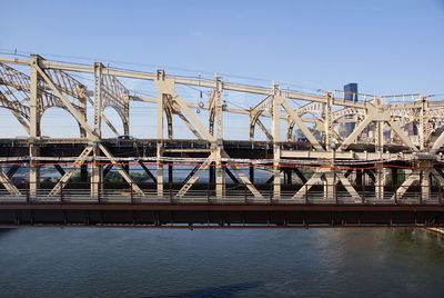 Bridge over river against sky in city