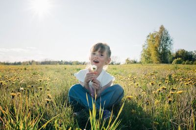 Young girl joyfully holding a flower in flower field in summer