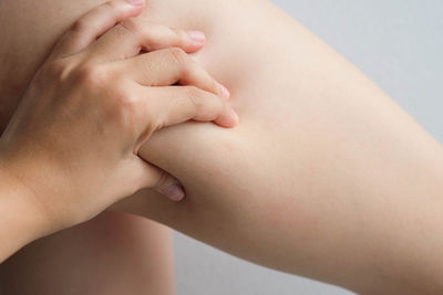 Cropped image of woman pinching thigh