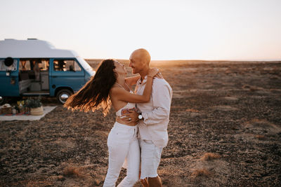 Rear view of couple kissing on land against sky