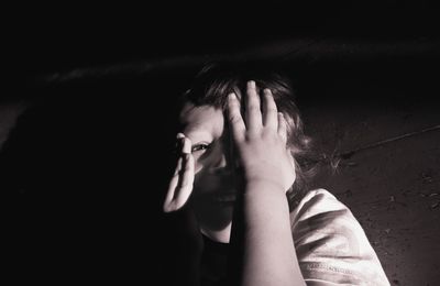 Close-up of depressed boy against black background