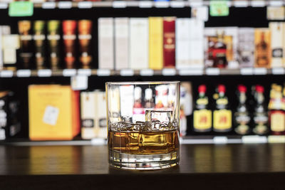 Whiskey with ice cubes in glass on bar counter