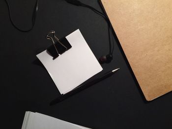 Directly above shot of blank paper with pen and in-ear headphones on table