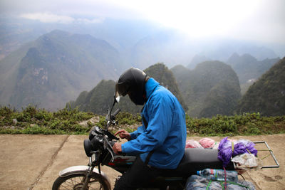 Man riding bicycle on mountain against sky