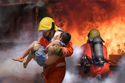 Young firefighter saving boy from fire