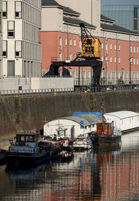 Sailboats moored on river by buildings in city